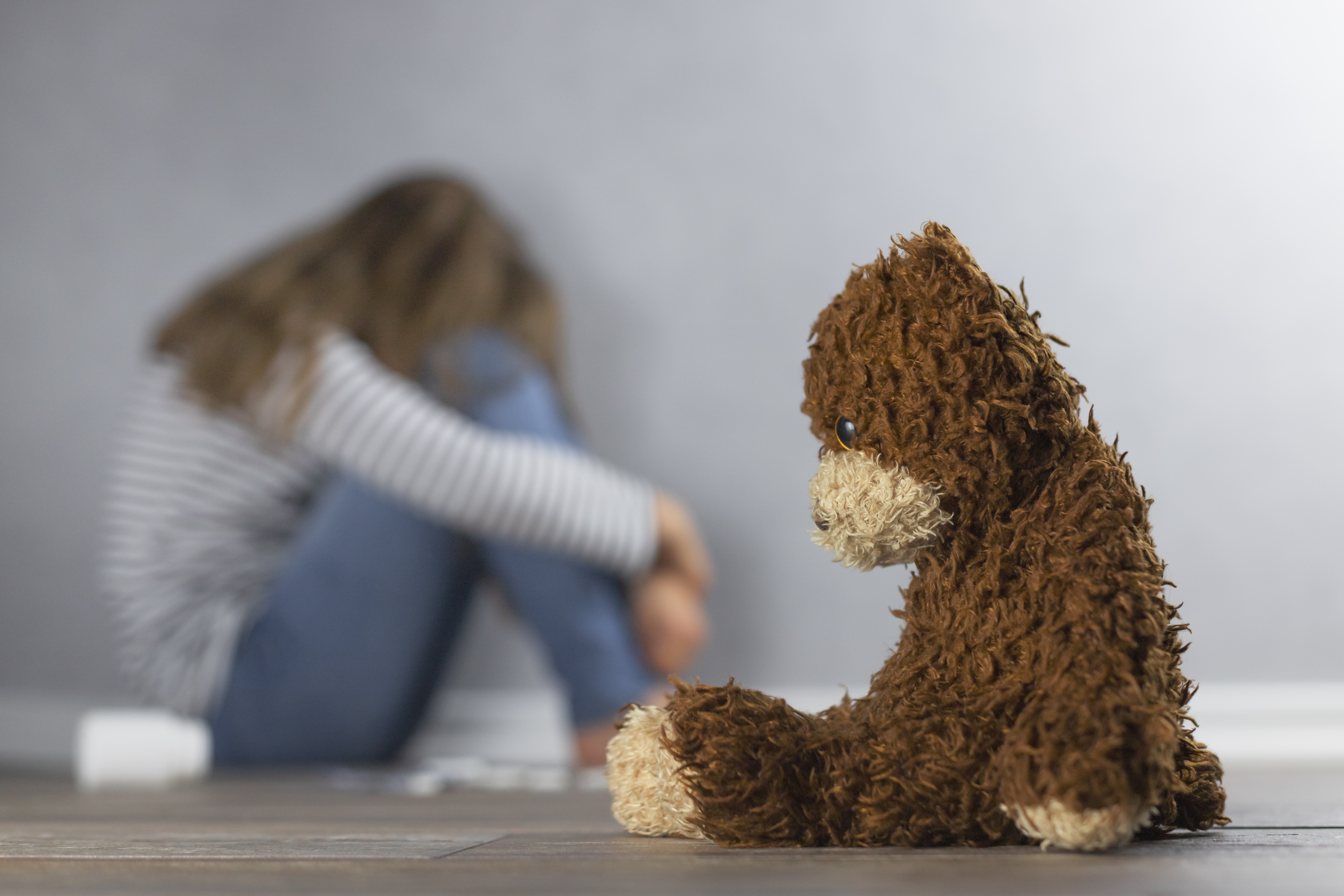 sad-child-with-teddy-bear-in-empty-room