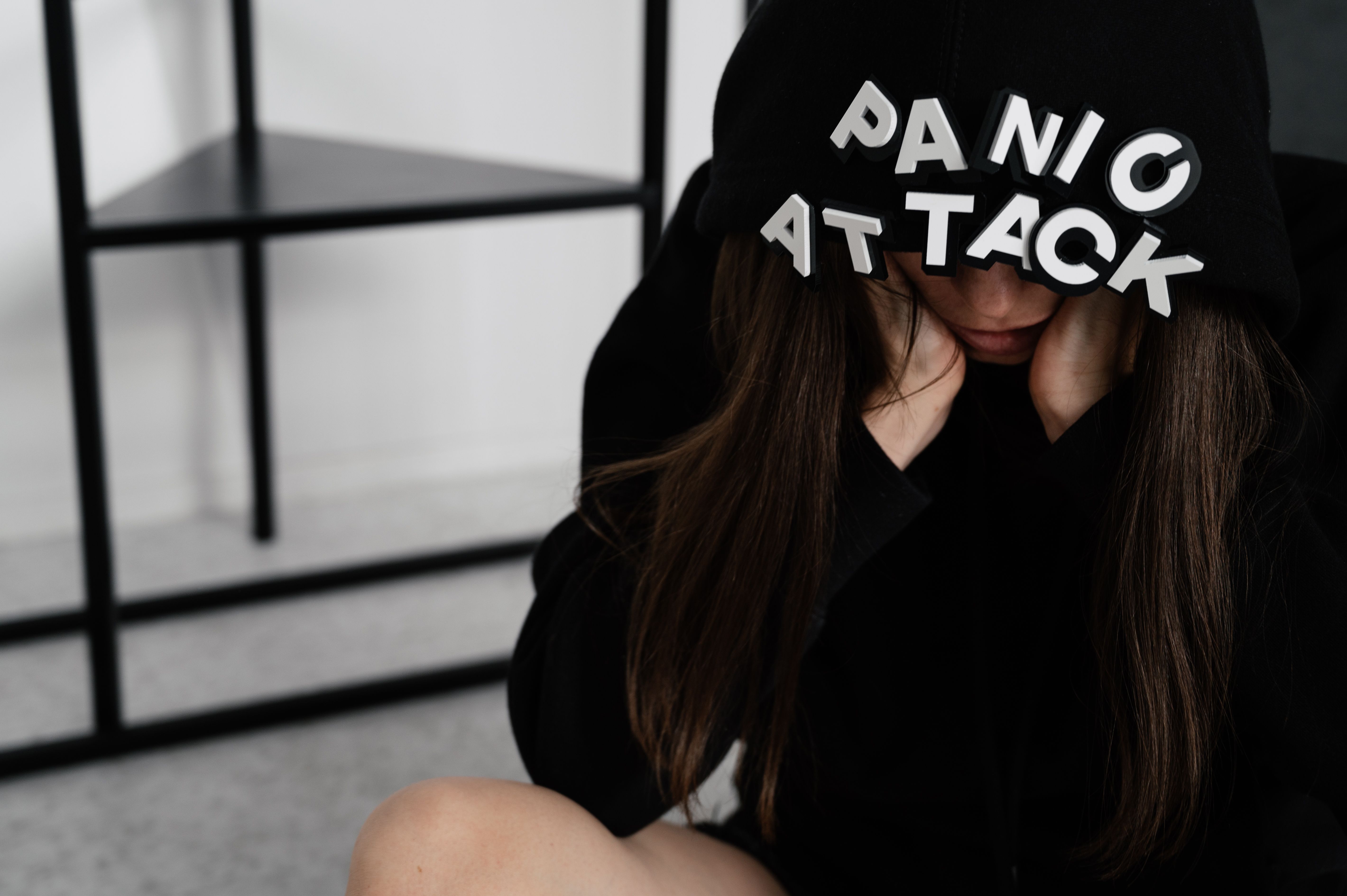 a girl sitting with a hoodie that says panic attack